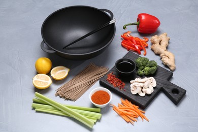 Photo of Wok, chopsticks and different products on grey table