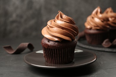 Photo of Delicious fresh chocolate cupcake on black slate table, closeup