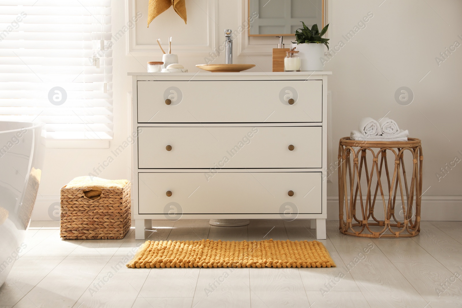 Photo of Stylish orange mat near chest of drawers in bathroom