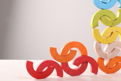 Photo of Colorful wooden pieces of playing set on white table against light grey background, space for text. Motor skills development