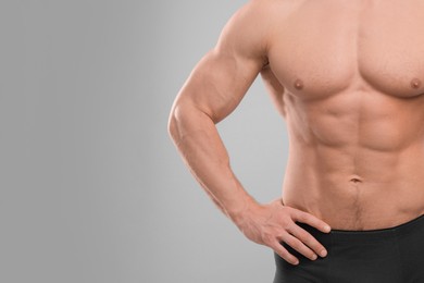 Photo of Muscular man showing abs on light grey background, closeup and space for text. Sexy body