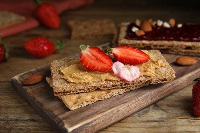 Fresh rye crispbreads with different toppings on wooden table, closeup