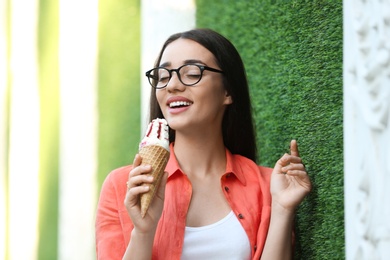 Photo of Happy young woman with delicious ice cream in waffle cone outdoors
