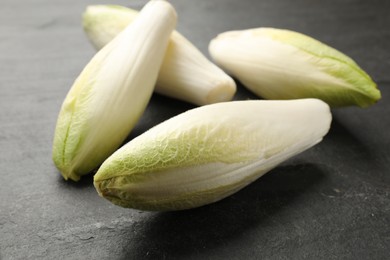 Photo of Fresh raw Belgian endives (chicory) on black table, closeup