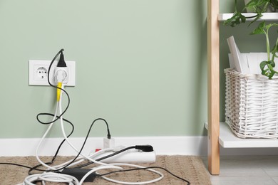 Photo of Different electrical plugs in socket and power strip on floor indoors. Space for text