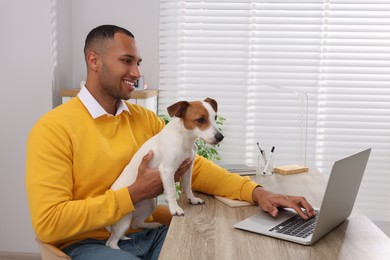 Photo of Young man with Jack Russell Terrier working at desk in home office