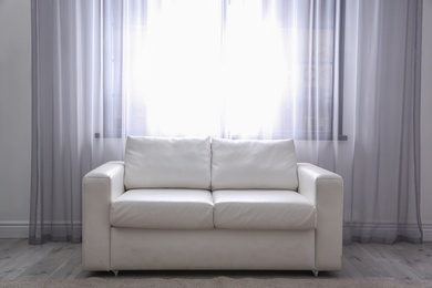 Photo of Simple living room interior with comfortable sofa near window. Space for text