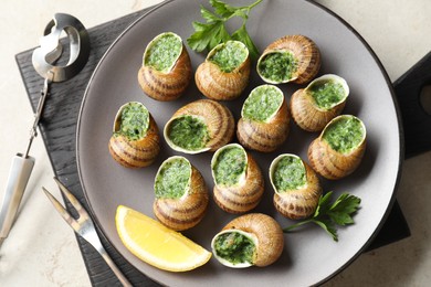 Photo of Delicious cooked snails served on light table, flat lay