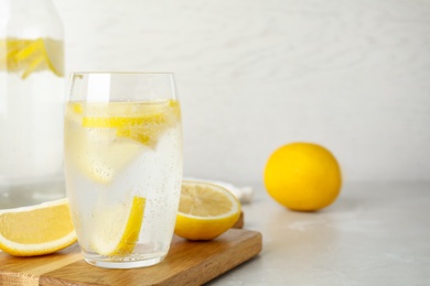 Photo of Soda water with lemon slices on light table. Space for text
