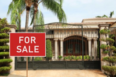 Image of Sale sign near beautiful house outdoors. Red signboard with words