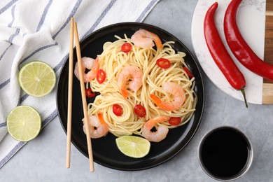 Photo of Tasty spaghetti with shrimps, chili pepper, lime and soy sauce on grey table, flat lay