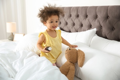 Photo of Cute African American child imagining herself as doctor while playing with toy bunny at home