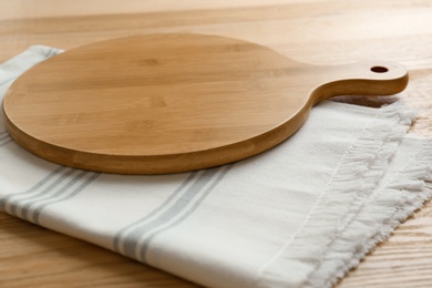 Photo of Empty wooden board and napkin on table, closeup