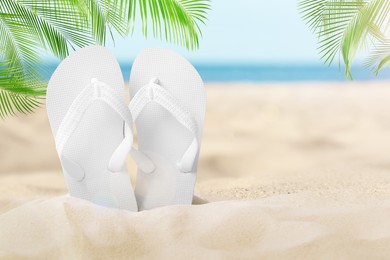 Image of White flip flops in sand on sandy beach near sea 