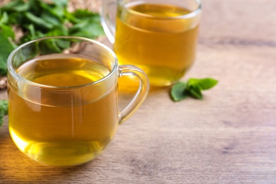 Photo of Fresh green tea with mint on wooden table, closeup. Space for text