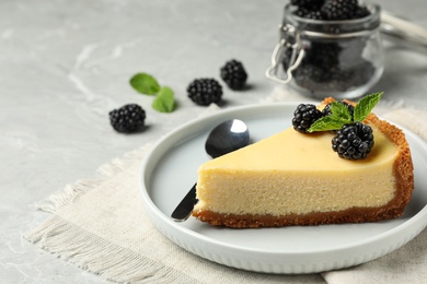Photo of Piece of delicious cheesecake with blackberries on light marble table
