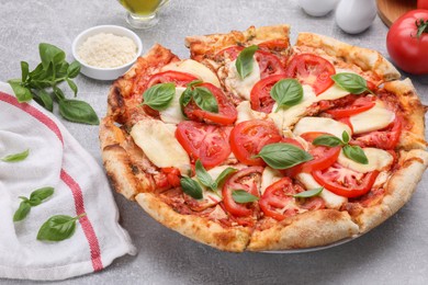 Photo of Delicious Caprese pizza and ingredients on grey table