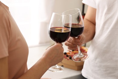 Photo of Couple clinking glasses of wine at home, closeup