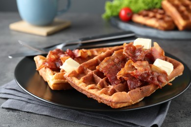 Tasty Belgian waffles served with bacon and butter on grey table, closeup