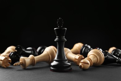 Photo of Black king among fallen chess pieces on dark background