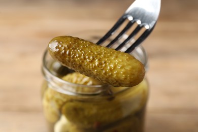 Photo of Eating tasty pickled cucumber at table, closeup