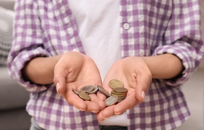 Photo of Woman holding coins at home, focus on hands, closeup