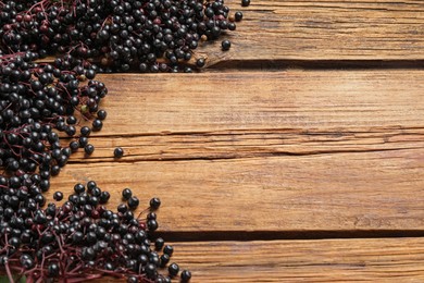 Photo of Elderberries (Sambucus) on wooden table, flat lay. Space for text
