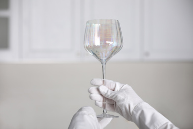 Photo of Person in white gloves checking cleanliness of glass indoors, closeup. Space for text