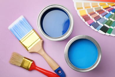 Photo of Flat lay composition with open cans of paint on color background