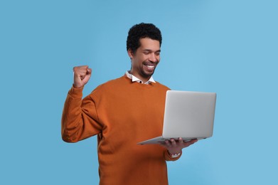 Photo of Happy man with laptop on light blue background