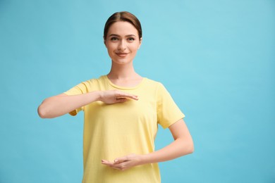 Photo of Young woman holding hands near chest on turquoise background, closeup. Space for text