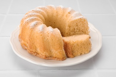 Photo of Delicious freshly baked sponge cake on white tiled table, closeup