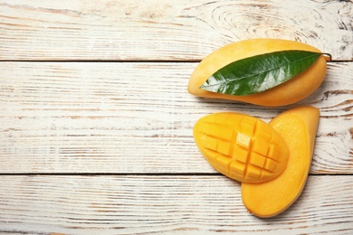 Photo of Flat lay composition with mango fruits on wooden background. Space for text