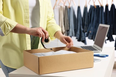 Photo of Seller preparing package at workplace, closeup. Online store