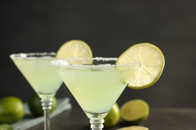 Photo of Delicious Margarita cocktail with salt and lime against blurred background, closeup