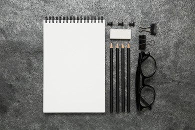Photo of Flat lay composition with blank sketchbook on grey stone table. Space for text