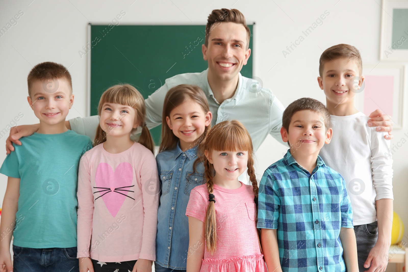 Photo of Cute little children with teacher in classroom at school