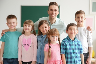 Photo of Cute little children with teacher in classroom at school