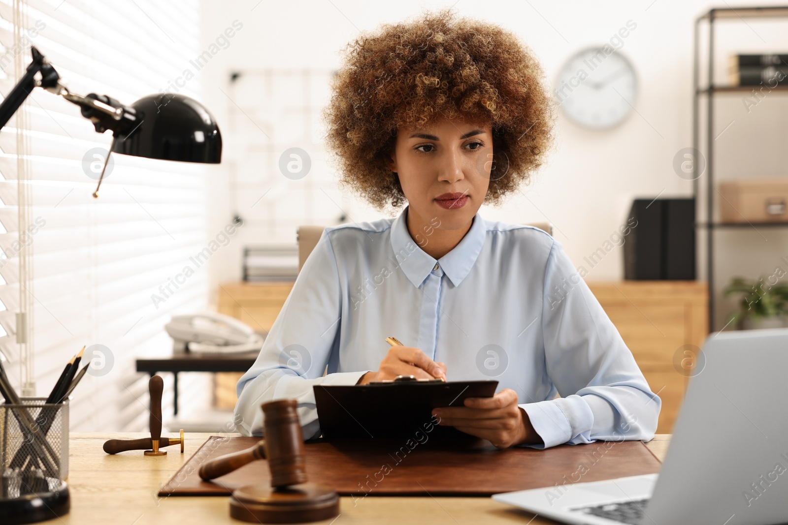 Photo of Notary with clipboard writing notes at workplace in office