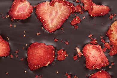 Photo of Chocolate bar with freeze dried strawberries as background, closeup