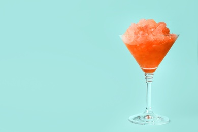 Photo of Shaving ice in martini glass on light blue background, space for text