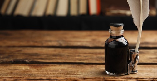 Image of Quill and bottle of ink on wooden table, space for text. Banner design