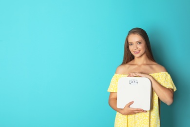 Photo of Beautiful young woman with scales on color background. Healthy diet
