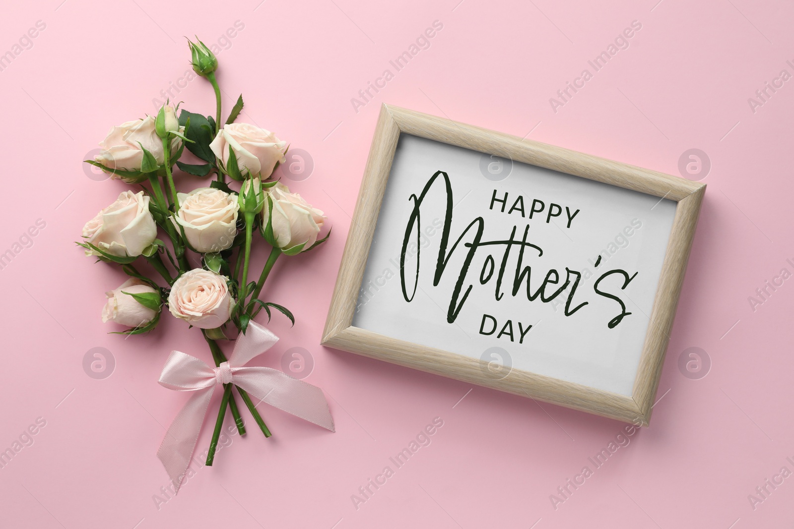 Image of Happy Mother's Day greeting card. Bouquet of beautiful roses and white board with wish on pink background, flat lay