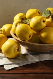 Photo of Tasty ripe quince fruits in bowl on wooden table