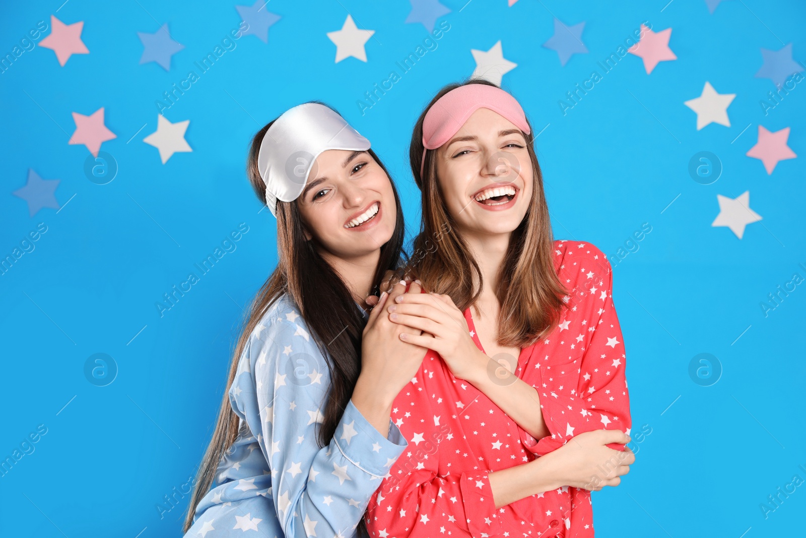 Beautiful women wearing sleeping masks on light blue background. Bedtime Photo of Beautiful women wearing sleeping masks on light blue background. Bedtime