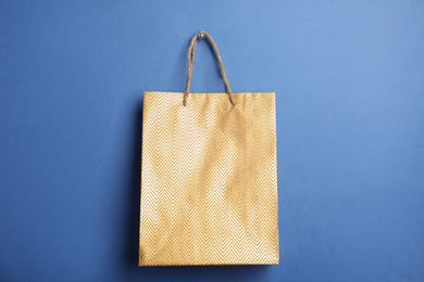 Photo of Gold shopping paper bag on blue background