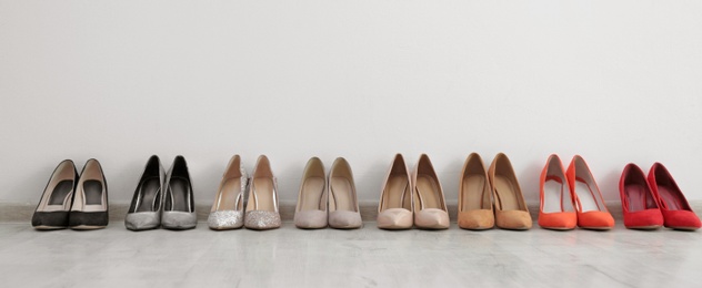 Photo of Collection of elegant shoes on floor at wall, space for text