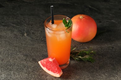 Photo of Tasty grapefruit drink with ice and mint in glass on dark textured table