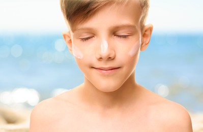 Image of Sun protection. Boy with sunblock on his face near sea, closeup